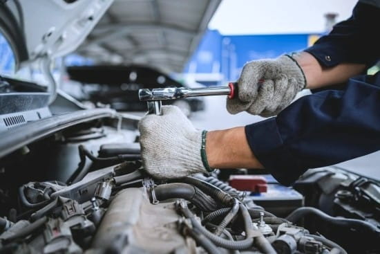 Skilled mechanic performing engine repair with tools in a professional auto shop.