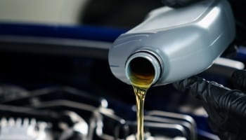 Close-up of engine oil being poured during a vehicle oil change at Suttons Custom Automotive.