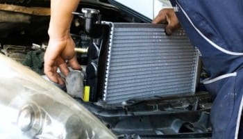 Technician installing a new radiator in a vehicle at Suttons Custom Automotive.