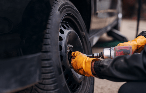 Tire technician inspecting a car tire with a power tool at Tatlow Tire.