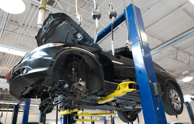 Car undergoing mechanical repairs on a lift at Tatlow Tire.