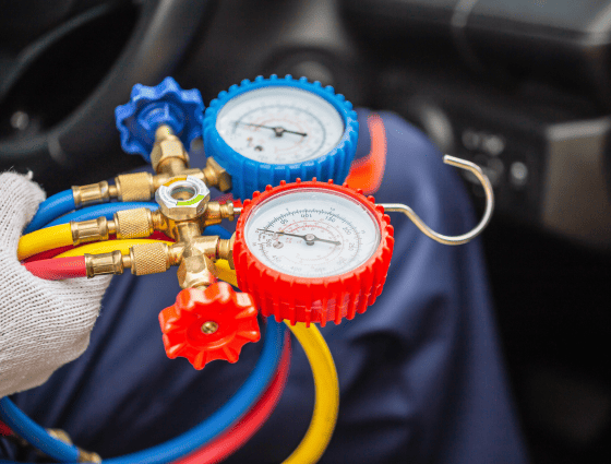 Automotive AC recharge with gauges and hoses for optimal cooling.
