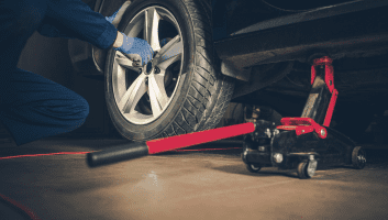Technician replacing a car tire with tools at Teays Valley Auto.