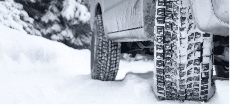 Winter tire tread on vehicle in snow for optimal traction and safety.