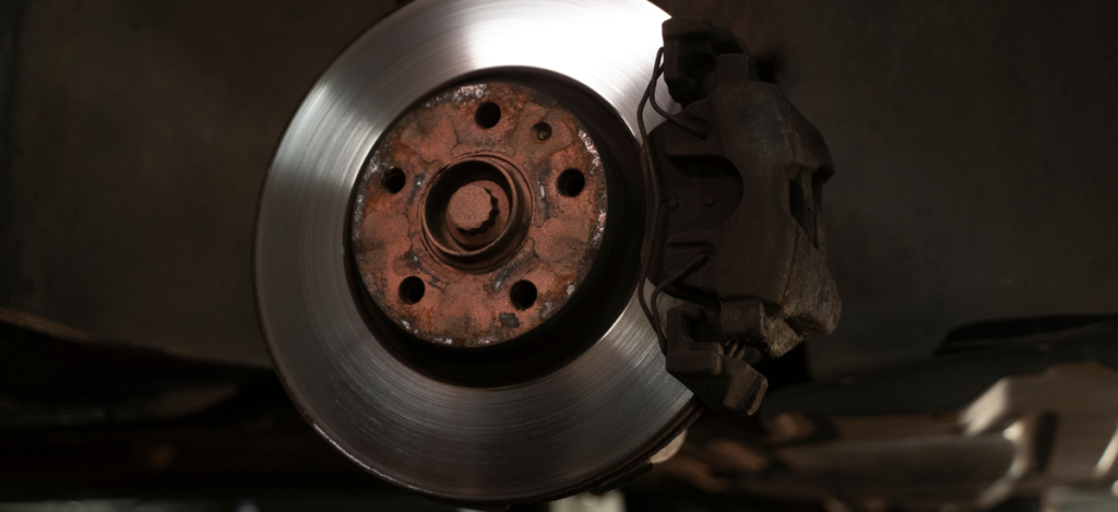 Brake rotor and caliper with rust and wear, highlighting common brake system issues.