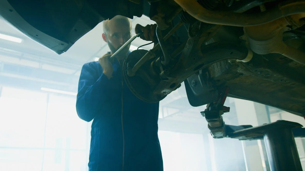 Mechanic inspecting vehicle shocks and struts for signs of wear and damage.