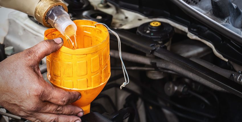 Engine oil being poured into a car engine for fluid change service.