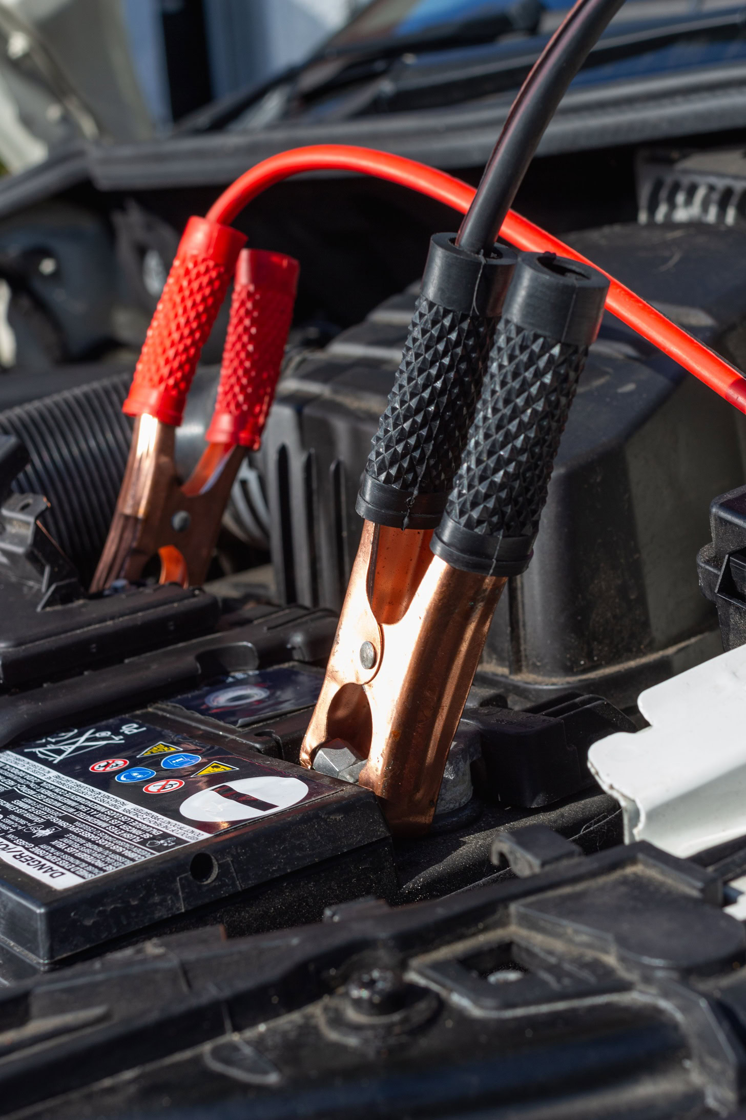 Car battery jump start cables connected to a vehicle's battery for testing or charging.