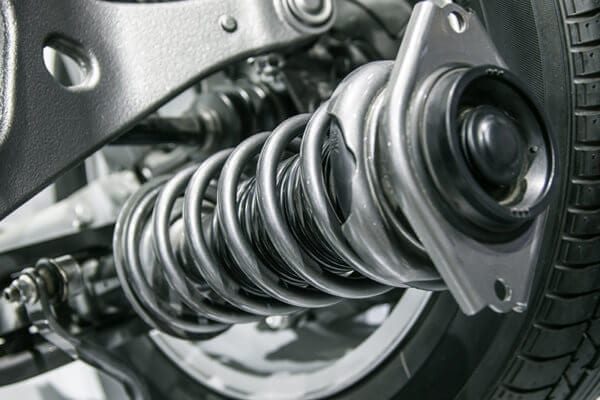 Close-up of vehicle suspension coil spring and shock absorber.