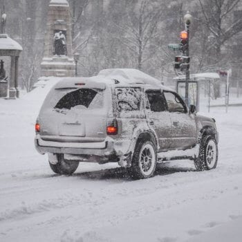Snow-covered SUV at Techline Motors during winter weather.