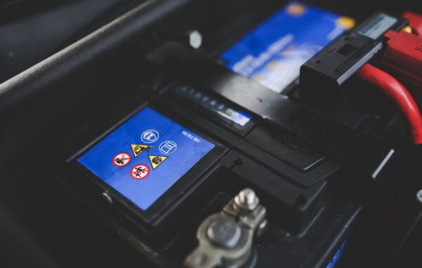 Car battery with warning labels at Techline Motors NAPA Autopro.