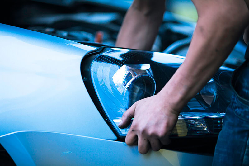 Technician inspecting a car headlight at Techline Motors NAPA Autopro.