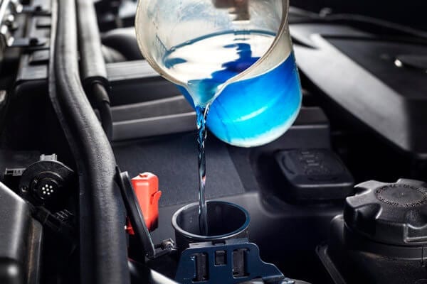 Engine coolant being poured into a car engine at Techline Motors.