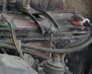 Dirty car battery with corrosion and cables in need of cleaning.