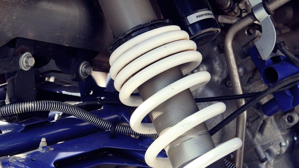Close-up of vehicle suspension system with coil spring and shock absorber.