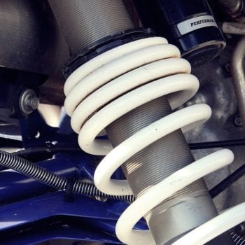 Close-up of vehicle suspension system with coil spring and shock absorber.