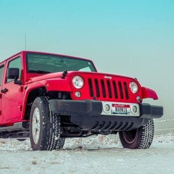 Red Jeep parked in snowy landscape at Techline Motors, NAPA Autopro shop.