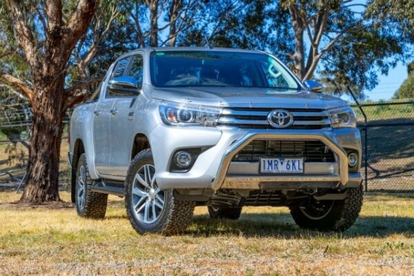 Silver Toyota pickup truck parked outdoors with trees in background.