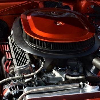 Close-up of a vintage car engine with red accents at Techline Motors.