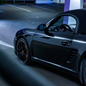 Black sports car parked in a well-lit parking lot at night.