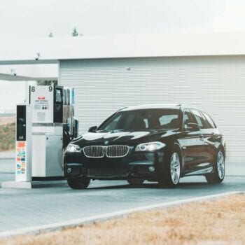 Black gasoline car refueling at a modern gas station.