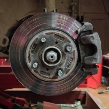 Close-up of a disc brake rotor and caliper at Techline Motors.