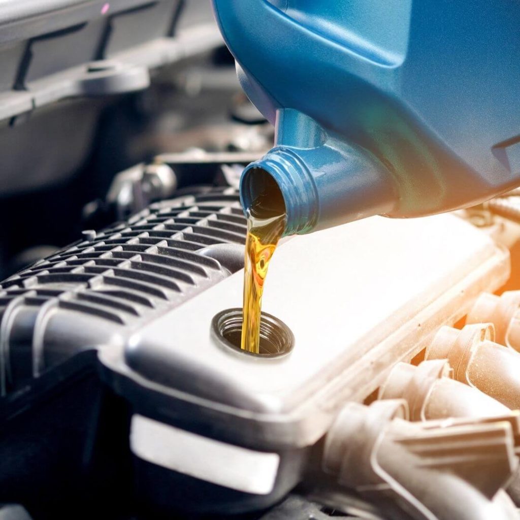 Pouring new oil into a car engine during maintenance at Techline Motors.