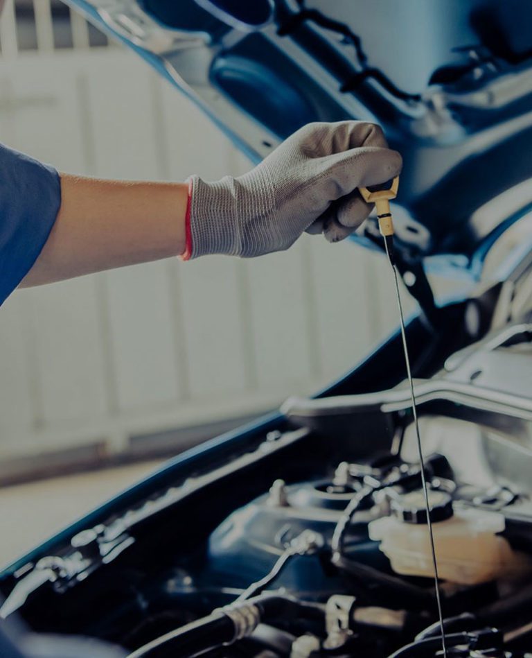 Technician checking oil level in Subaru engine during service.