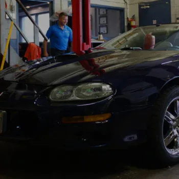Black sports car inside Techline Motors NAPA Autopro Shop with technician.