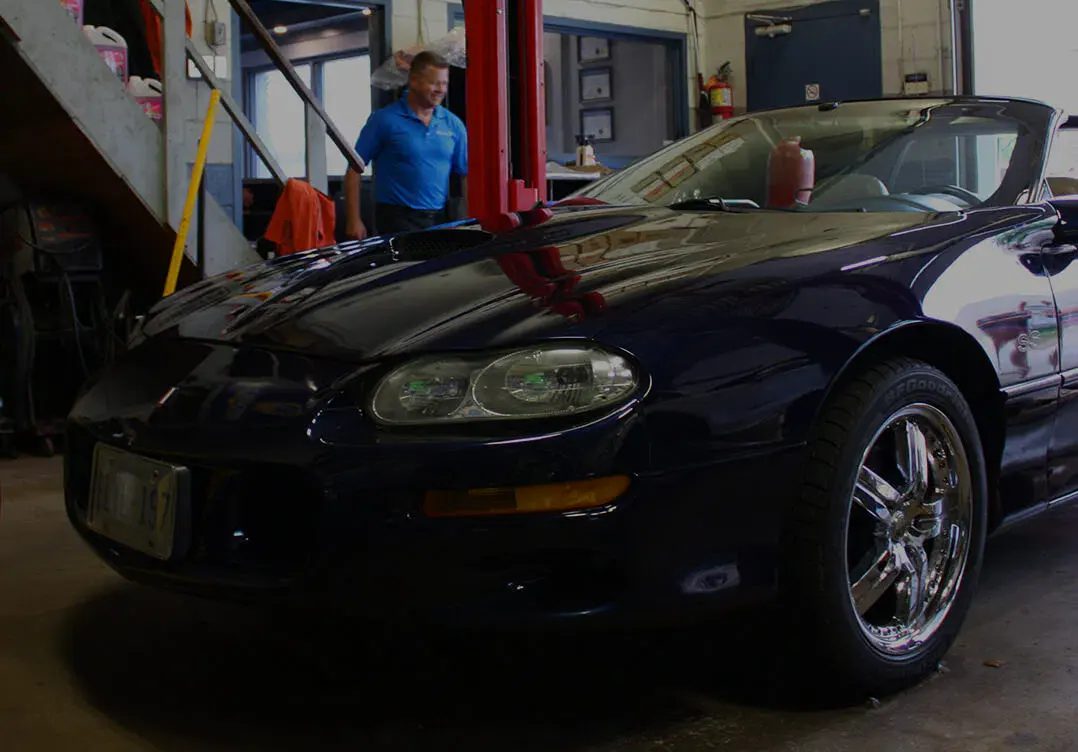 Black sports car inside Techline Motors NAPA Autopro Shop with technician.