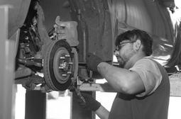 Skilled auto repair technician inspecting vehicle brake system.