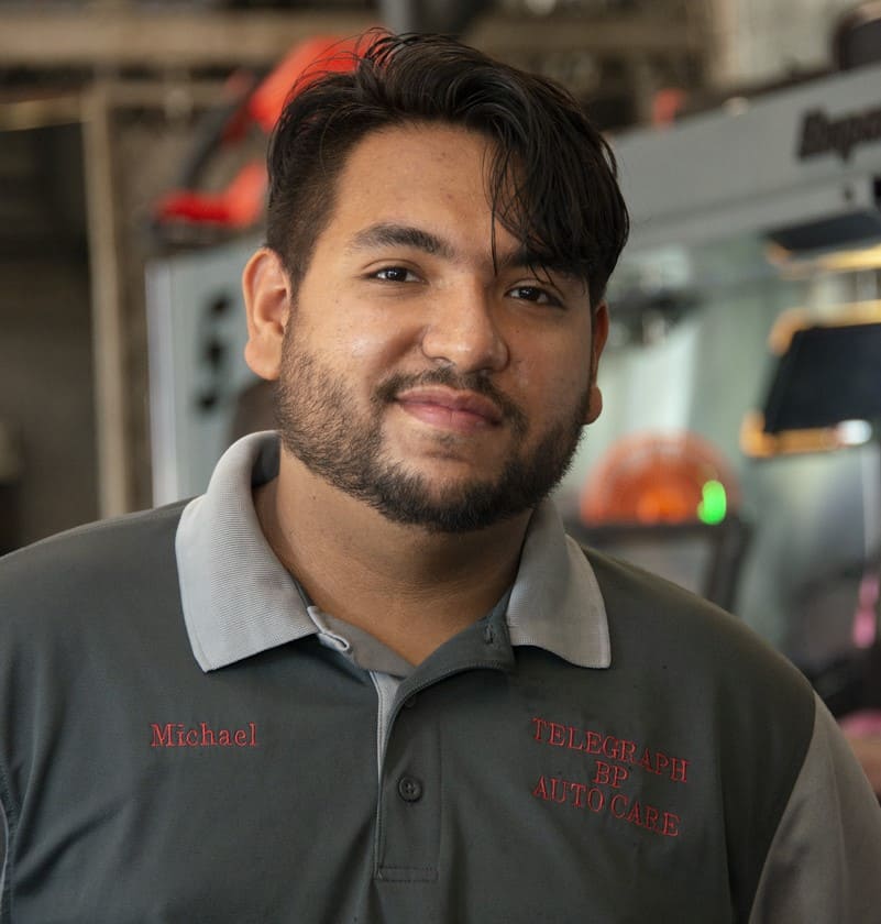 Friendly mechanic at Telegraph Auto Repair workshop, smiling confidently.