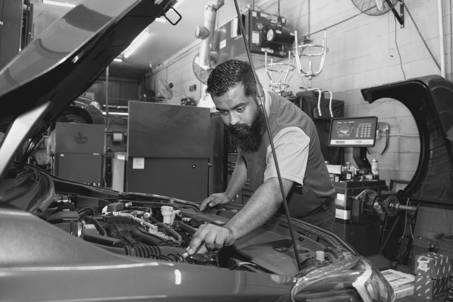 Skilled mechanic inspecting car engine in auto repair shop.