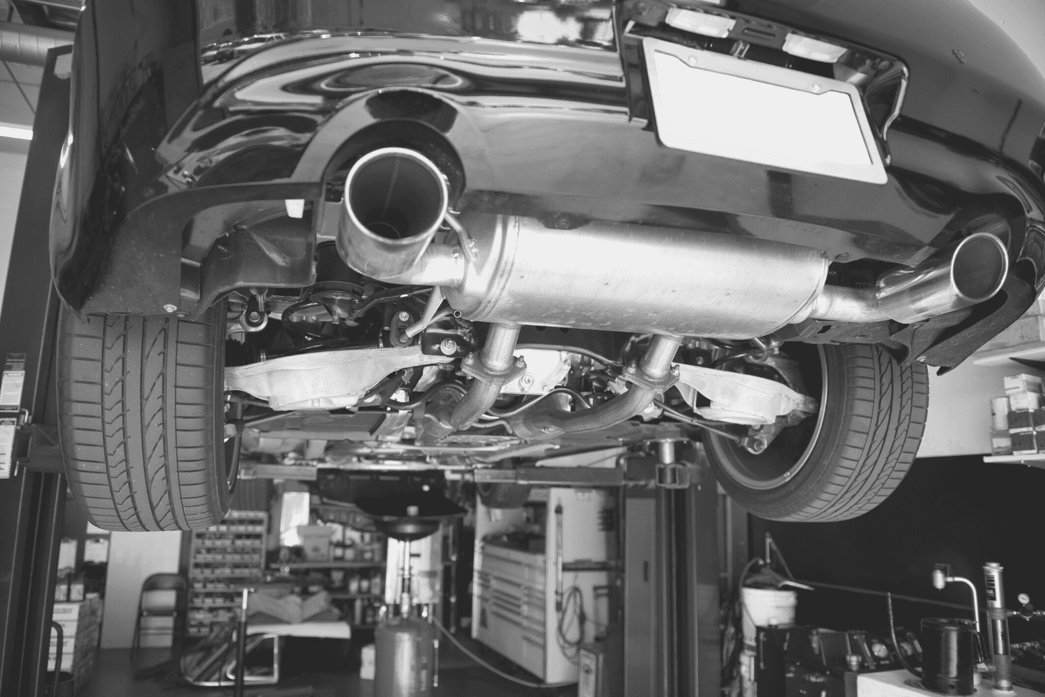Car exhaust system being serviced in auto repair shop.
