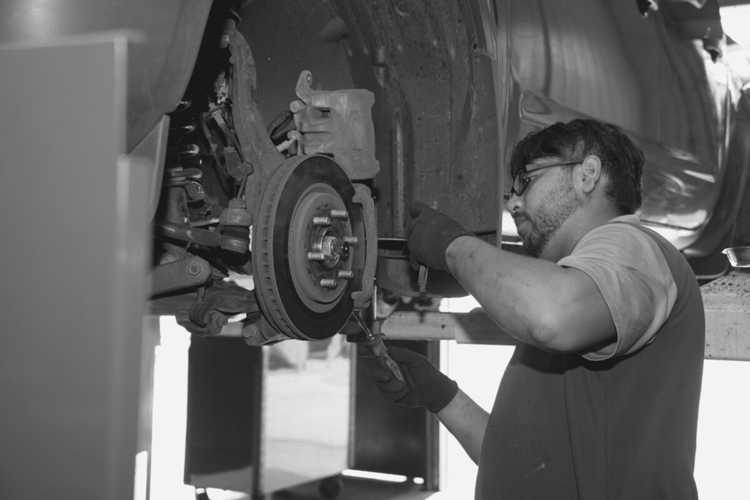 Auto repair technician inspecting and repairing a vehicle's brake components.