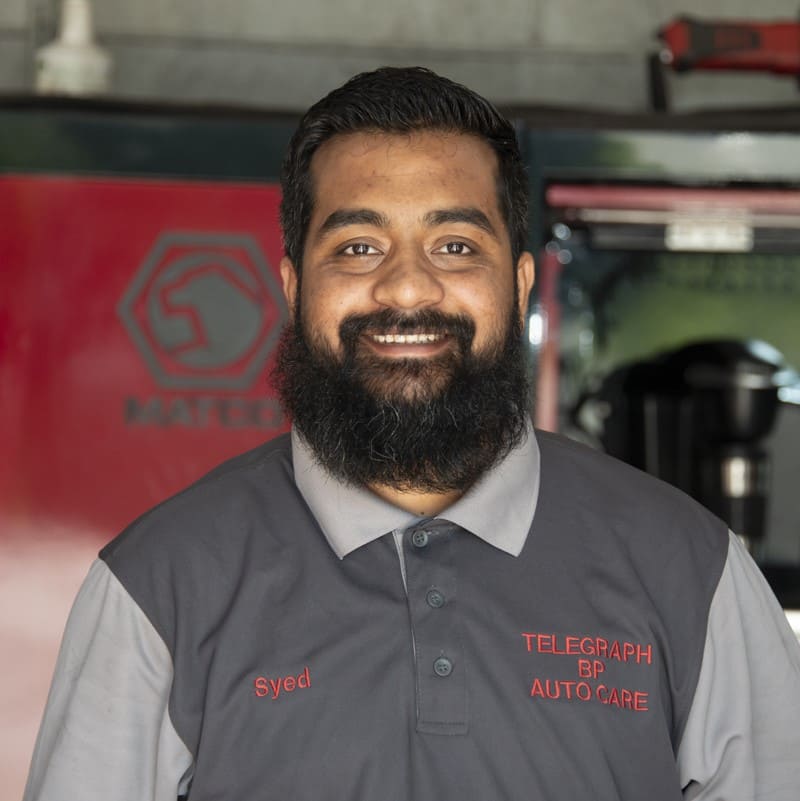 Auto repair technician smiling at workshop.