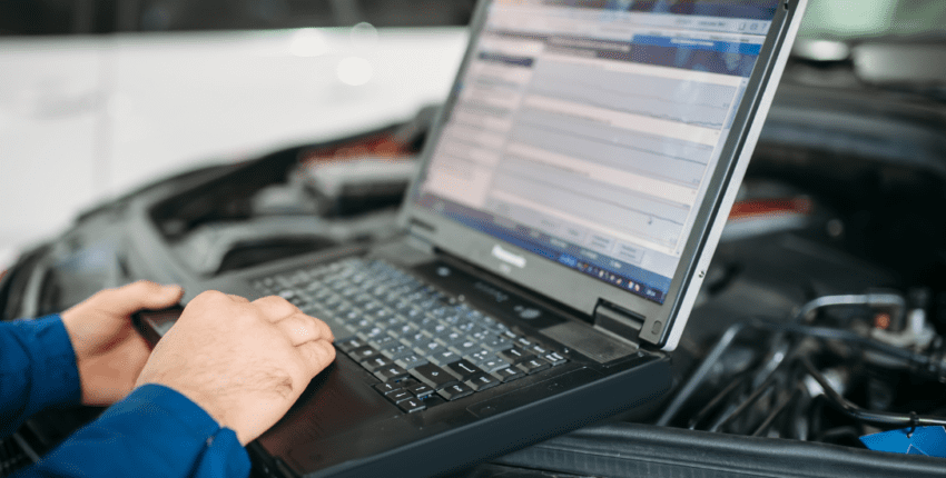 Technician using diagnostic scanner on vehicle engine for advanced auto repair.