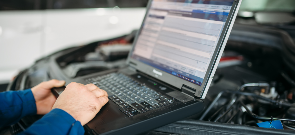 Technician using diagnostic scanner on vehicle engine for advanced auto repair.