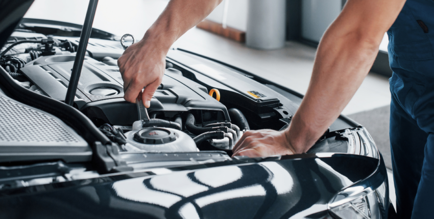 Auto electrical repair technician working on a vehicle's engine.