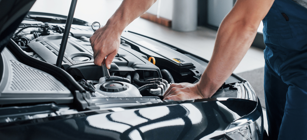 Auto electrical repair technician working on a vehicle's engine.