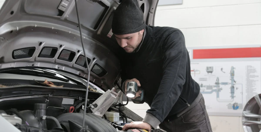 Auto mechanic inspecting engine for repair or maintenance services.