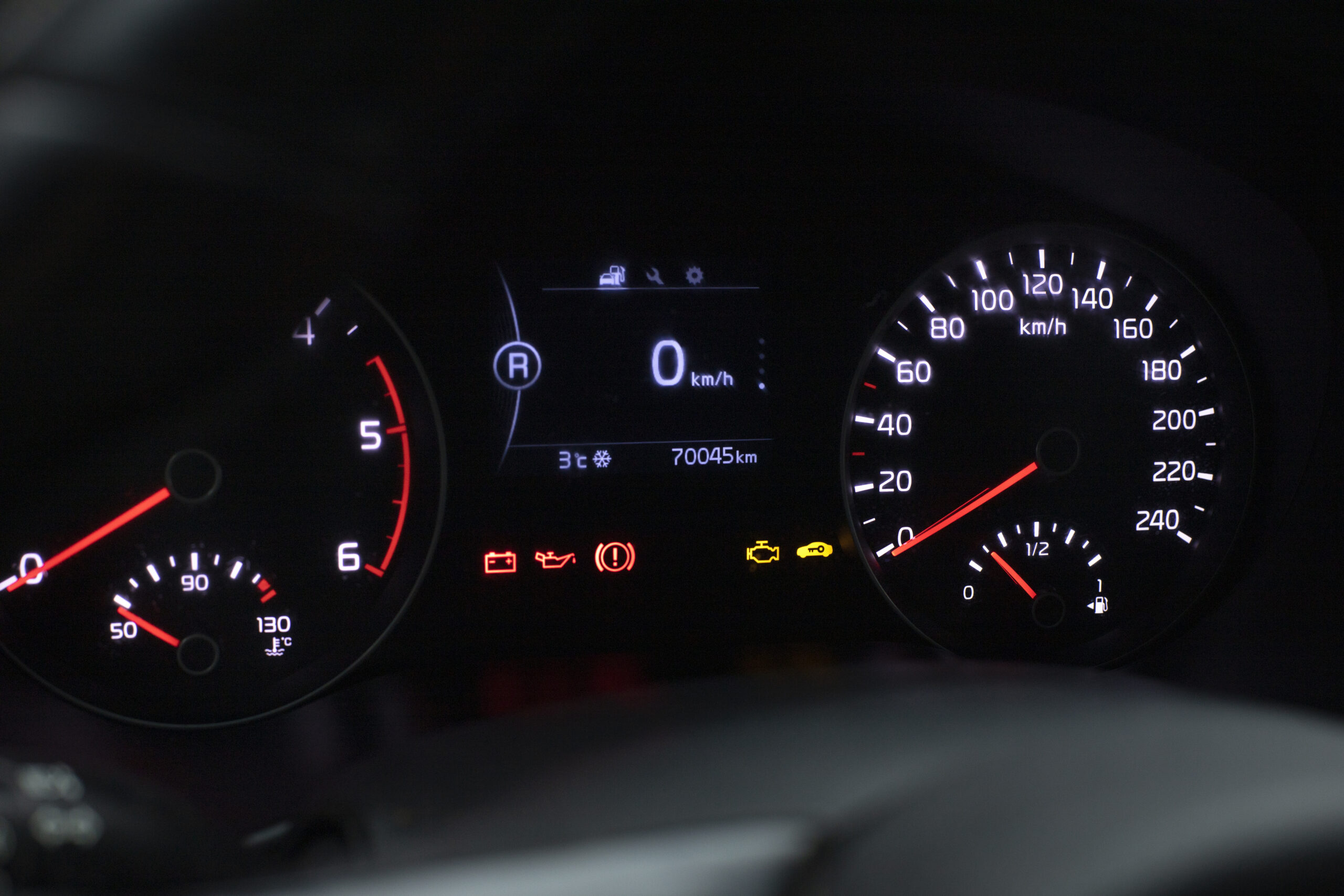 Car dashboard showing battery warning light and check engine indicators.