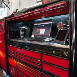 Auto repair workstation with tools, laptop, and diagnostic equipment in a garage setting.