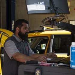 Auto repair technician diagnosing vehicle issues in a garage.