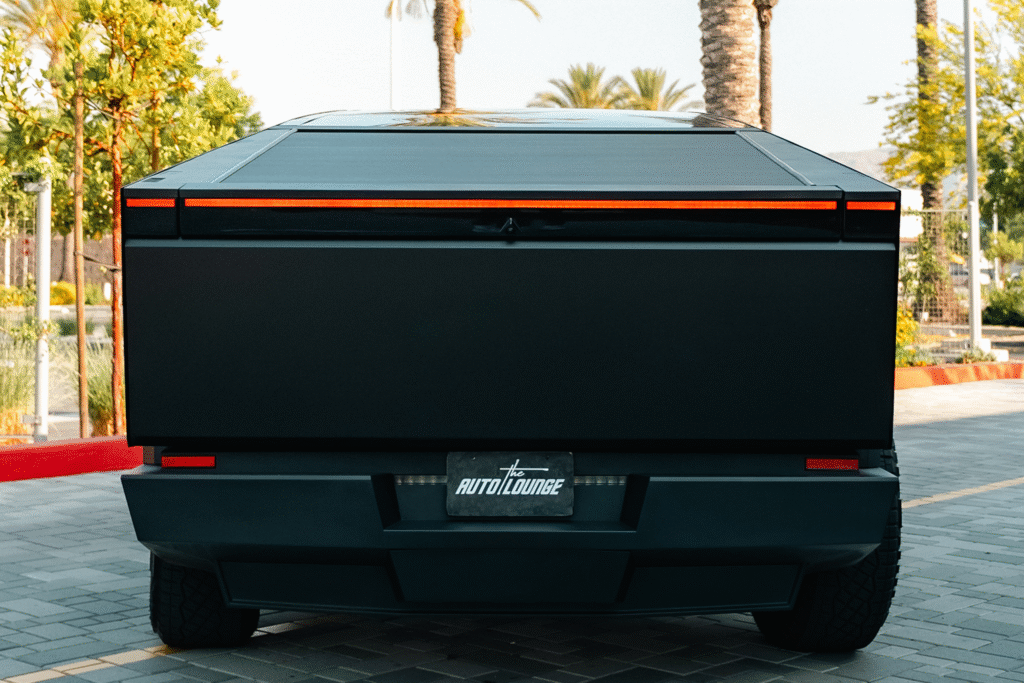 Black custom truck bed cover with orange accents, parked in a sunny lot.