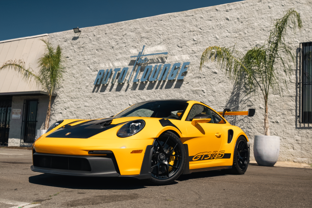 Yellow Porsche 911 GT3 RS parked outside Auto Lounge dealership.