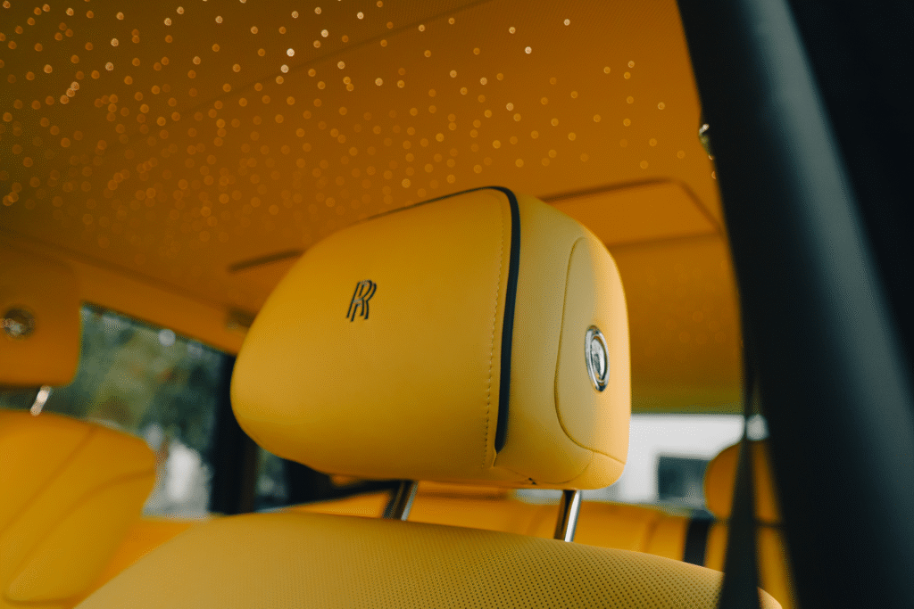 Luxury yellow car interior headrest with Rolls-Royce logo at The Auto Lounge.