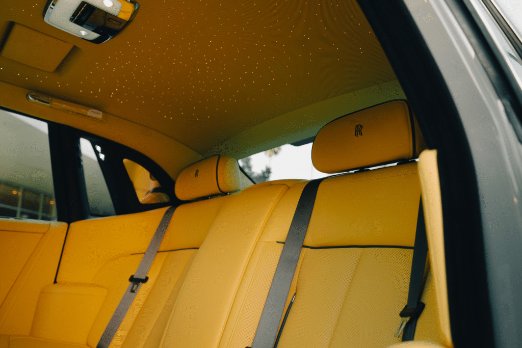Interior view of a luxury vehicle with yellow leather seats and a starry ceiling design.
