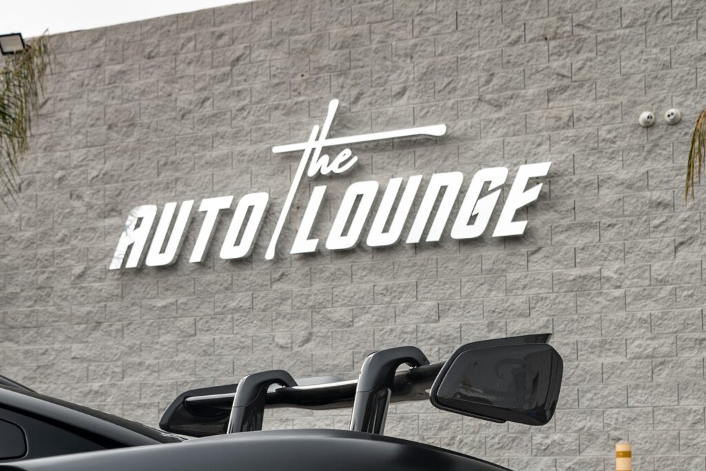 Auto Lounge gallery sign on textured wall.
