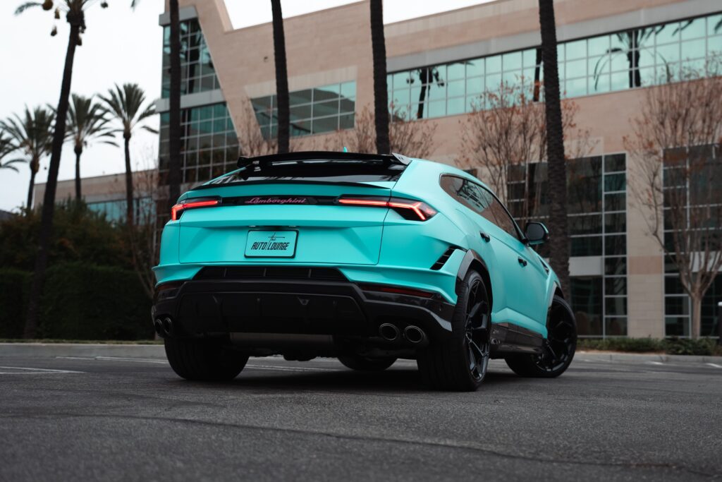 Blue Lamborghini Urus SUV parked outdoors near modern office building.